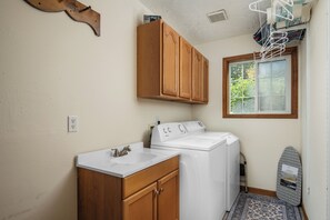 A compact laundry room with a washing machine, dryer, and a small sink.