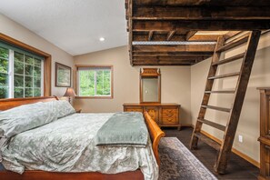A bedroom with a wooden bed, a dresser, a mirror, and a ladder.