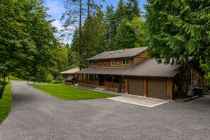 A two-story wooden cabin with a covered porch and a garage.