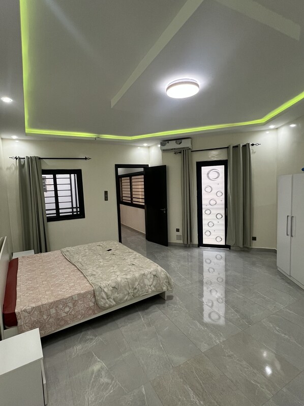 A modern bedroom with a bed, a wardrobe, and a door leading to another room. - Spacious Cocooning Villa in Dakar (Dakar)