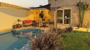 A modern outdoor living area with a pool, seating, and a dining area.