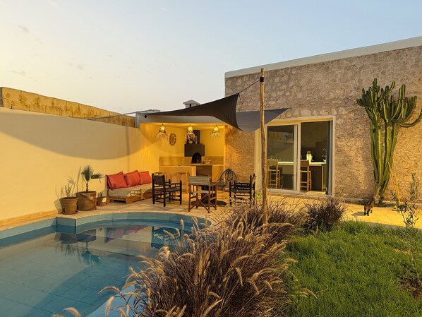 A modern outdoor living area with a pool, seating, and a dining area. - Serenity Mogador (Essaouira)