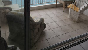 Un balcone con vista sul mare, una sedia a dondolo e un tavolino con una pianta.