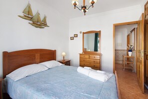A bedroom with a wooden bed, a dresser, a mirror, and a chandelier.