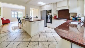 A modern kitchen with white cabinetry, a granite countertop, and a built-in oven. - 5bed Surrey home · Games Room · Near Thorpe Park - Pass the Keys (Surrey)