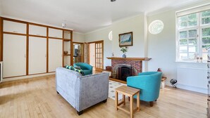 A spacious living room with a fireplace, wooden flooring, and a large window. - 5bed Surrey home · Games Room · Near Thorpe Park - Pass the Keys (Surrey)