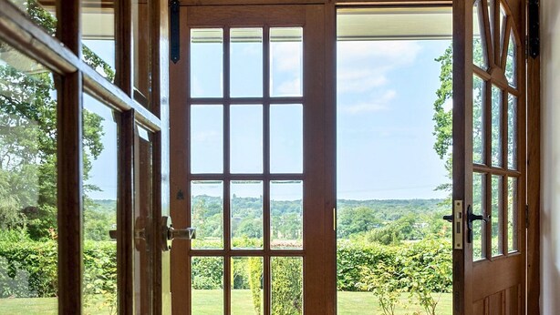 A wooden door with a grid pattern, leading to a view of a lush green landscape. - 5bed Surrey home · Games Room · Near Thorpe Park - Pass the Keys (Surrey)