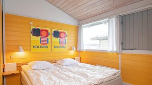 A room with a bed, two wall-mounted lamps, and two posters on the wall. - 6 Person Holiday Park Home in Hanstholm (Hanstholm)