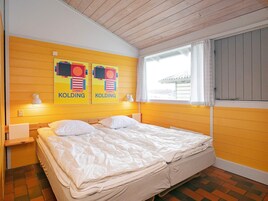 Una habitación con una cama, dos lámparas de pared y dos carteles en la pared.