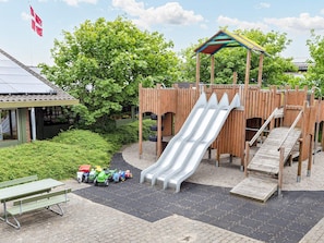 A playground with a slide, climbing area, and a picnic table with toy vehicles.