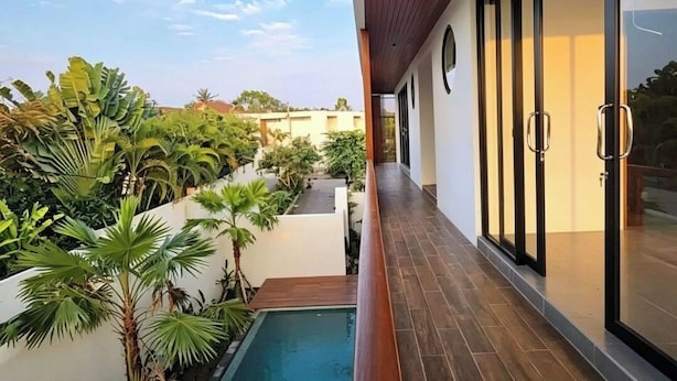 Un bâtiment moderne doté d’une piscine, d’une terrasse en bois et de portes vitrées.