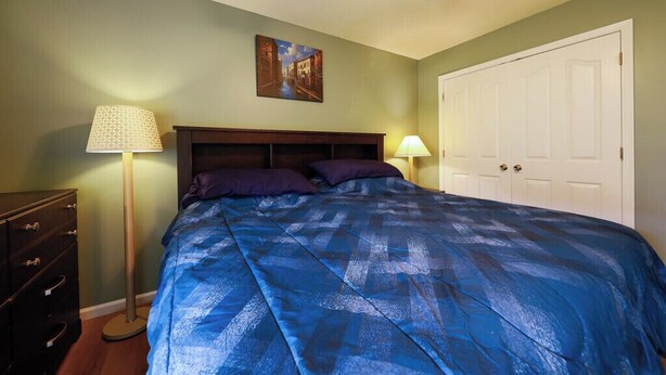 Una camera da letto con un letto, due lampade ai comodini, una cassettiera e una porta.