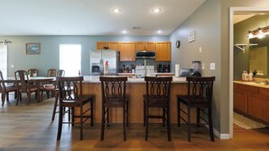 A modern kitchen with wooden cabinets, a central island with bar stools, and a dining area with wooden chairs. - Quiet, Family Friendly 3/2 Home (Columbia)