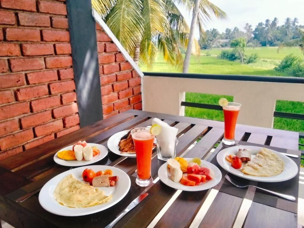 A table with breakfast items and a drink, set against a brick wall and a view of greenery.