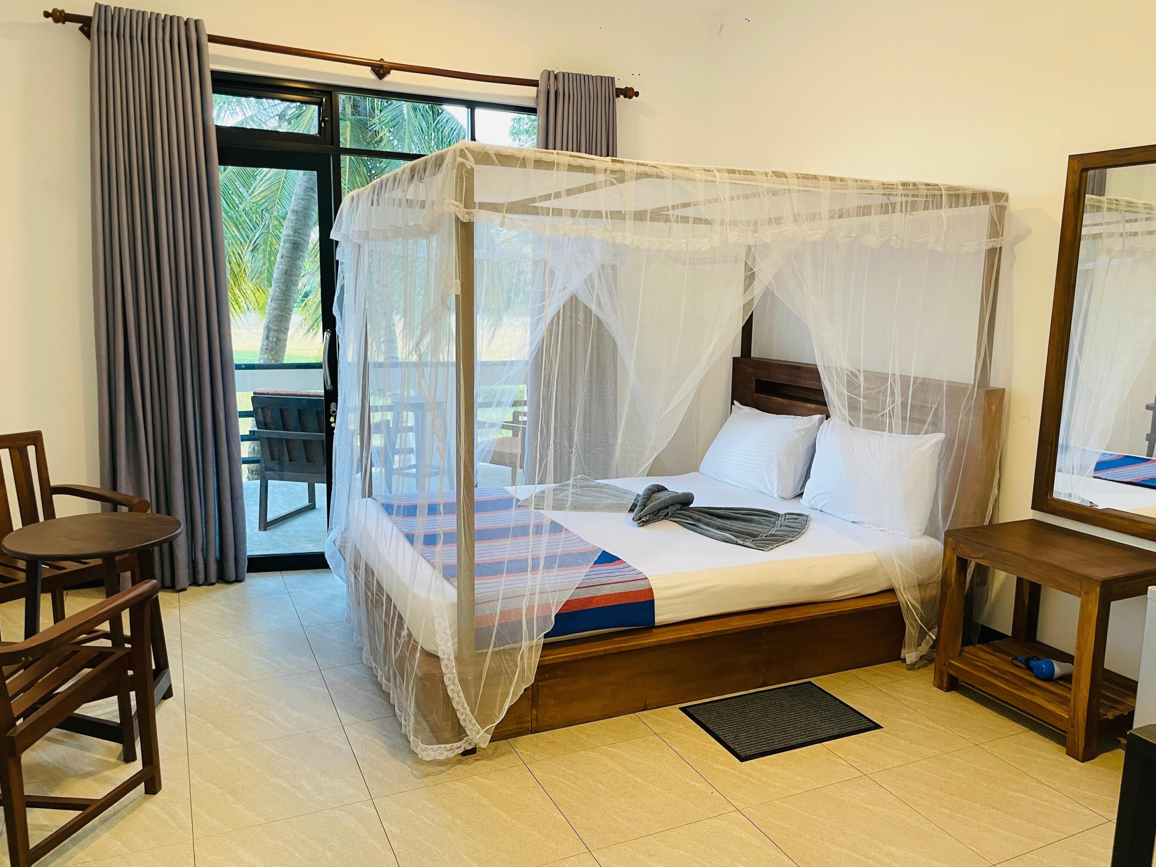 A bed with a canopy, a chair, a small table, and a mirror.