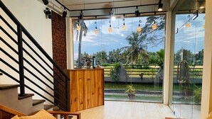 A spacious room with a wooden staircase, a chessboard on the floor, and a view of a garden through large windows. - Tranquil Sanctuary Yala (Tissamaharama)