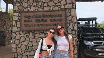 Un mur de pierre sur lequel est apposée une plaque indiquant « Parc national de Yala », et un SUV noir garé devant.