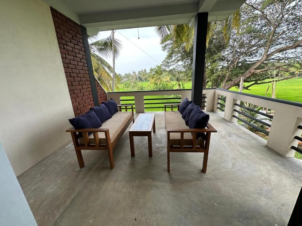 Un área de estar al aire libre con techo, con dos sofás de madera y una mesa, con vistas a un paisaje verde exuberante.