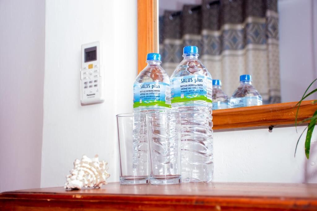 A bathroom with a mirror, a water dispenser, and a stack of clear glasses.