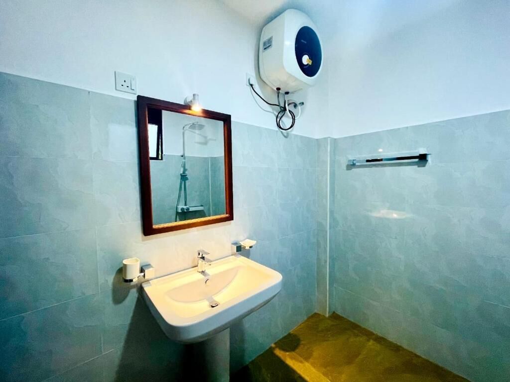 A bathroom with a sink, mirror, and hand dryer.