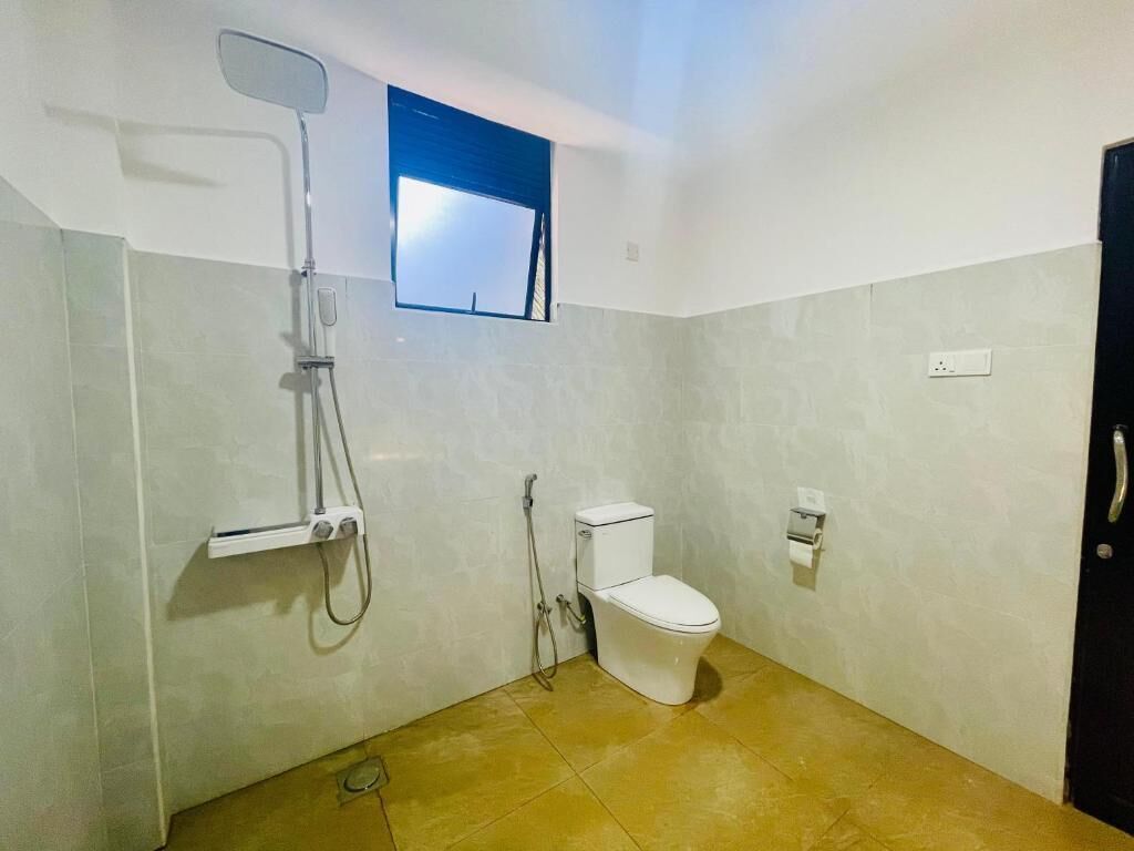 A small bathroom with a toilet, a shower, and a window.