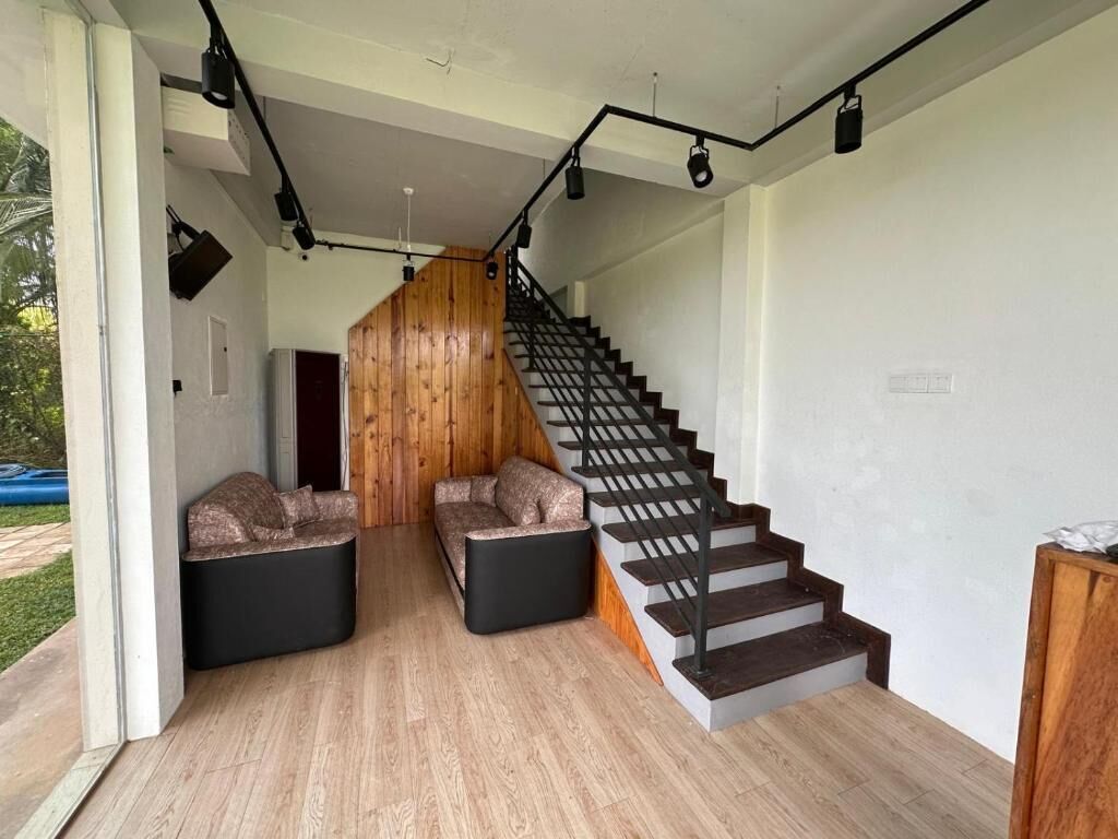 A modern interior with a staircase, two seating areas, and a wooden accent wall.