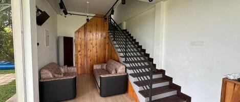 A modern interior with a staircase, two seating areas, and a wooden accent wall.