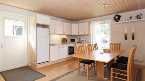 Una cocina moderna con armarios blancos, una mesa de comedor de madera y un tapete negro.