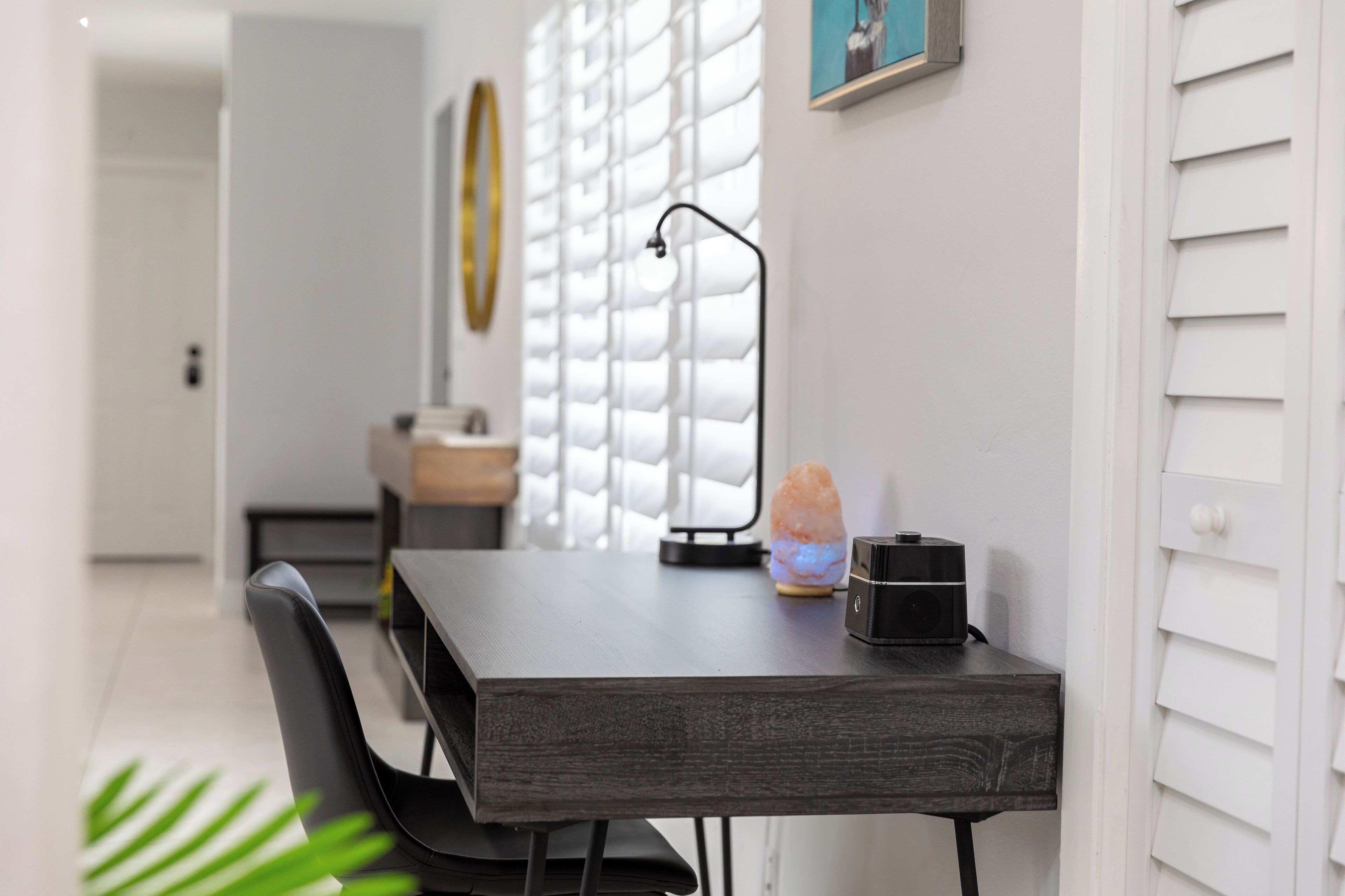Een moderne eetruimte met een donker houten tafel, zwarte stoelen, een zoutlamp en een kleine speaker.