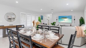 A modern dining area with a wooden table set for six, surrounded by black chairs.
