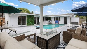 A covered patio area with a pool, outdoor furniture, and a view of the backyard.