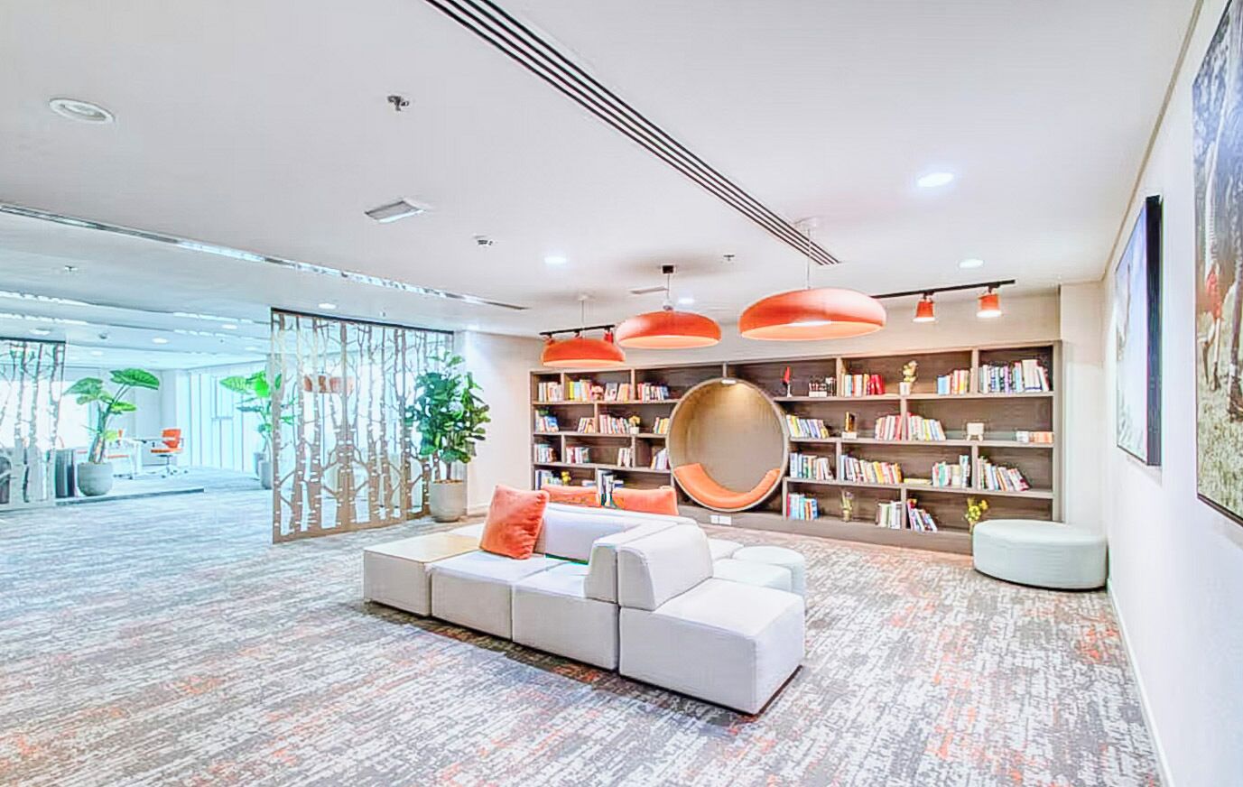 A modern interior with a sectional sofa, a large bookshelf, and a hanging light fixture.