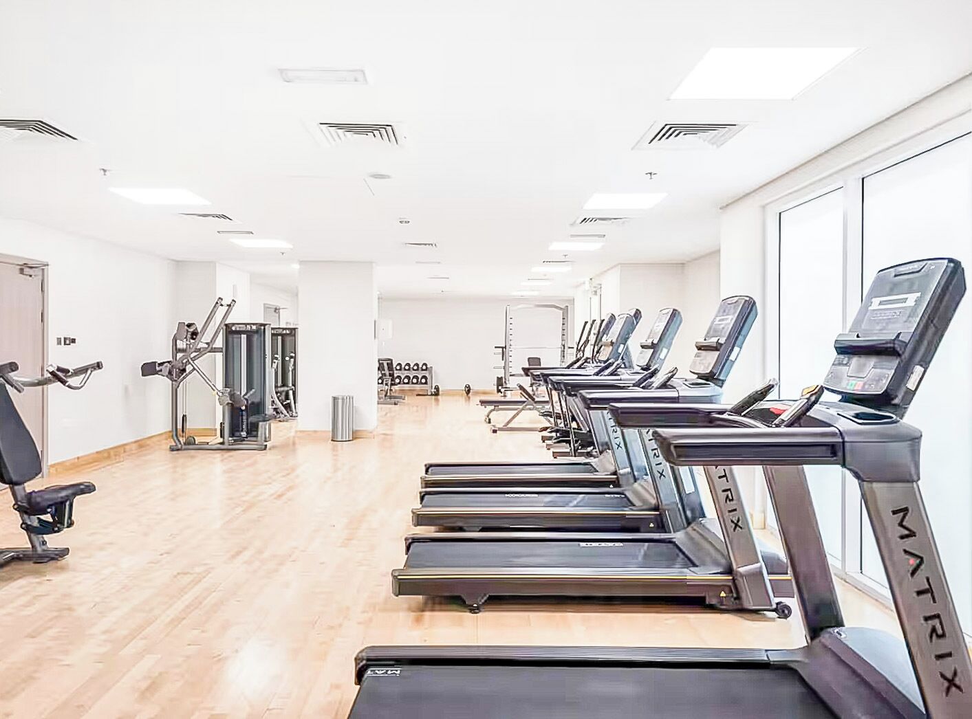Un gimnasio con cintas de correr, máquinas de pesas y un espejo.