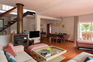 Una sala de estar con chimenea, sofá, comedor y una escalera.