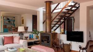 Ein Wohnzimmer mit Sofa, Couchtisch, Kamin, Fernseher und einer Treppe.