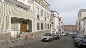 Una calle adoquinada flanqueada por edificios históricos, automóviles estacionados y un cielo despejado.