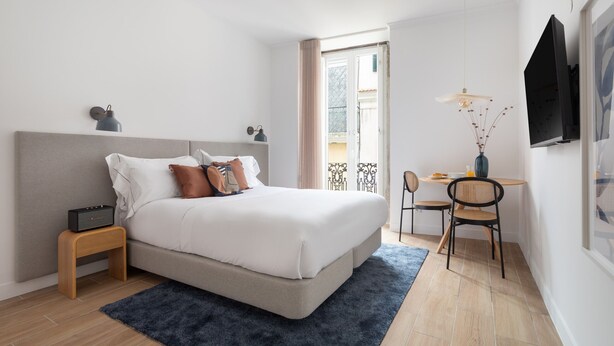 Un dormitorio moderno con cama, mesita de noche, lámpara y escritorio con silla.
