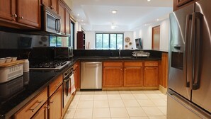 A modern kitchen with wooden cabinets, stainless steel appliances, and a black countertop.