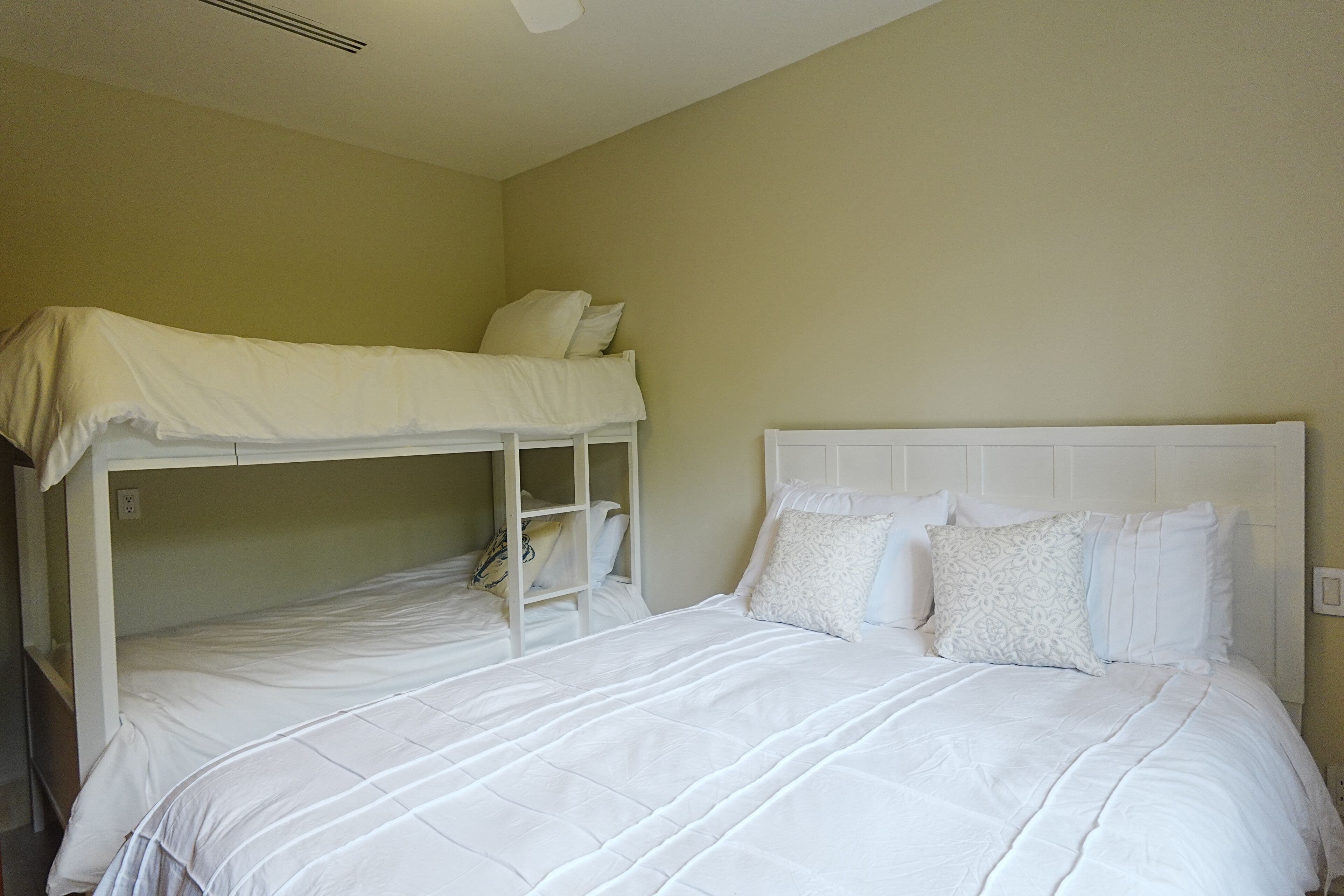 Une chambre avec un lit superposé et un lit simple, tous deux dotés de draps blancs.
