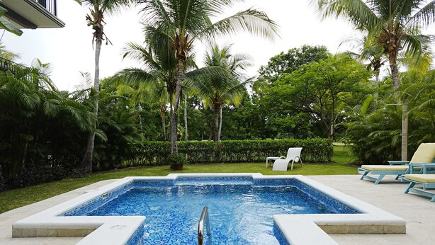 A rectangular swimming pool with a tiled edge, surrounded by a concrete deck.