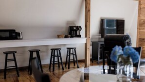 Moderni keittiö, jossa on mikroaaltouuni, kahvinkeitin ja baarituolit.