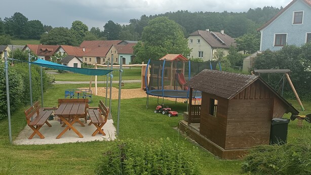Un parque infantil con columpios, tobogán y una casita de juegos.