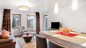 Un salon moderne comprenant un canapé, un fauteuil, une table à manger et un téléviseur.
