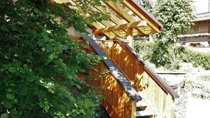 Une structure en bois dotée d’un toit en pente, entourée de verdure.