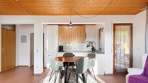 Et moderne køkken med træskabe, et rundt spisebord med stole og en hængende lampe.