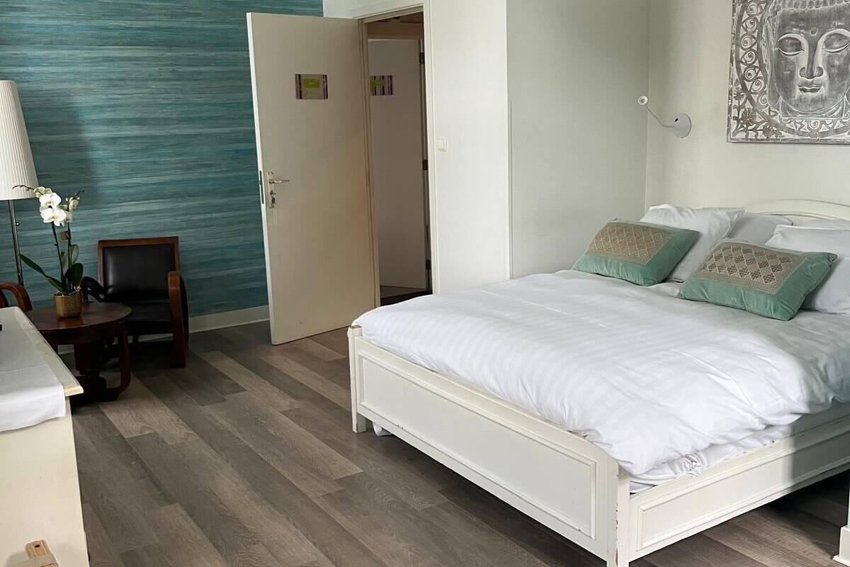 A bedroom with a bed, a desk, a chair, a lamp, and a wall with a textured design.