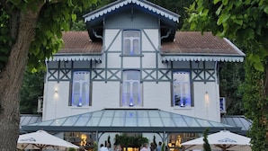 A traditional building with a symmetrical facade, large windows, and a covered outdoor area with umbrellas.