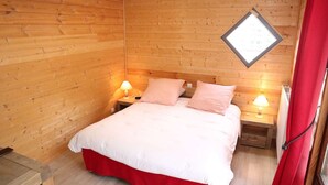 Ein Zimmer in einer Holzhütte mit einem Bett, zwei Nachttischen und einem Fenster mit Blick.