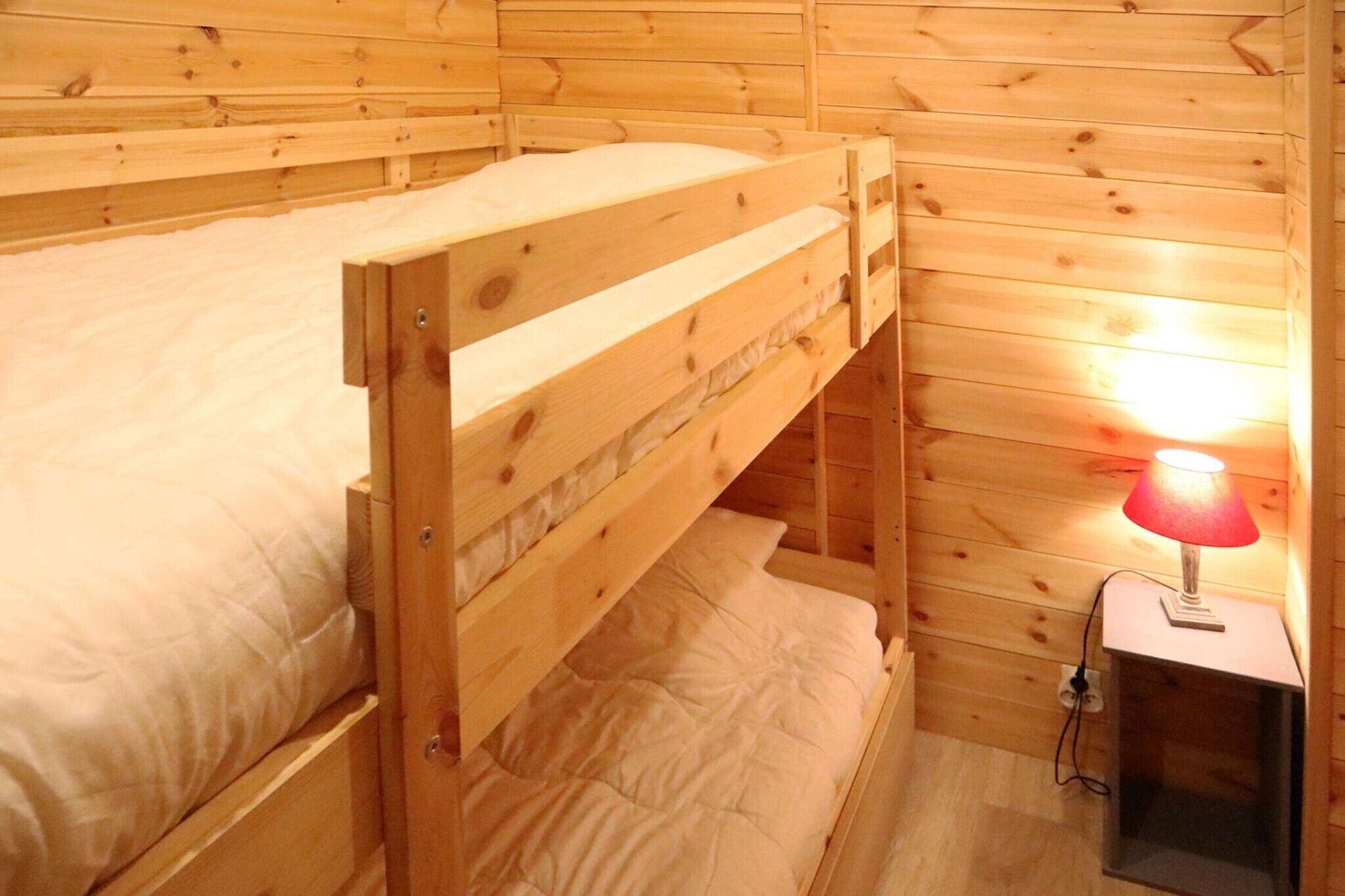 Un letto a castello in legno con una lampada rossa su un comodino.