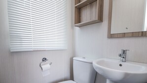 Un baño con inodoro, lavamanos y persianas.